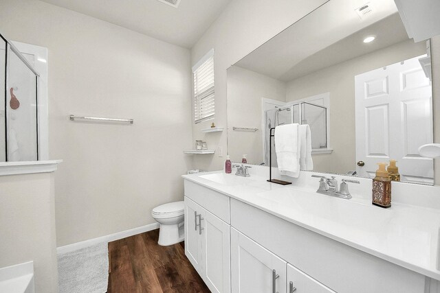 bathroom featuring toilet, a shower with door, vanity, and hardwood / wood-style flooring