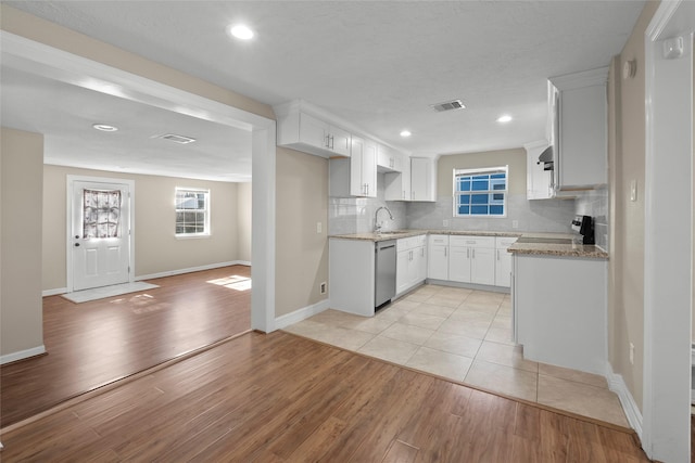 kitchen with decorative backsplash, white cabinets, sink, dishwasher, and light hardwood / wood-style floors