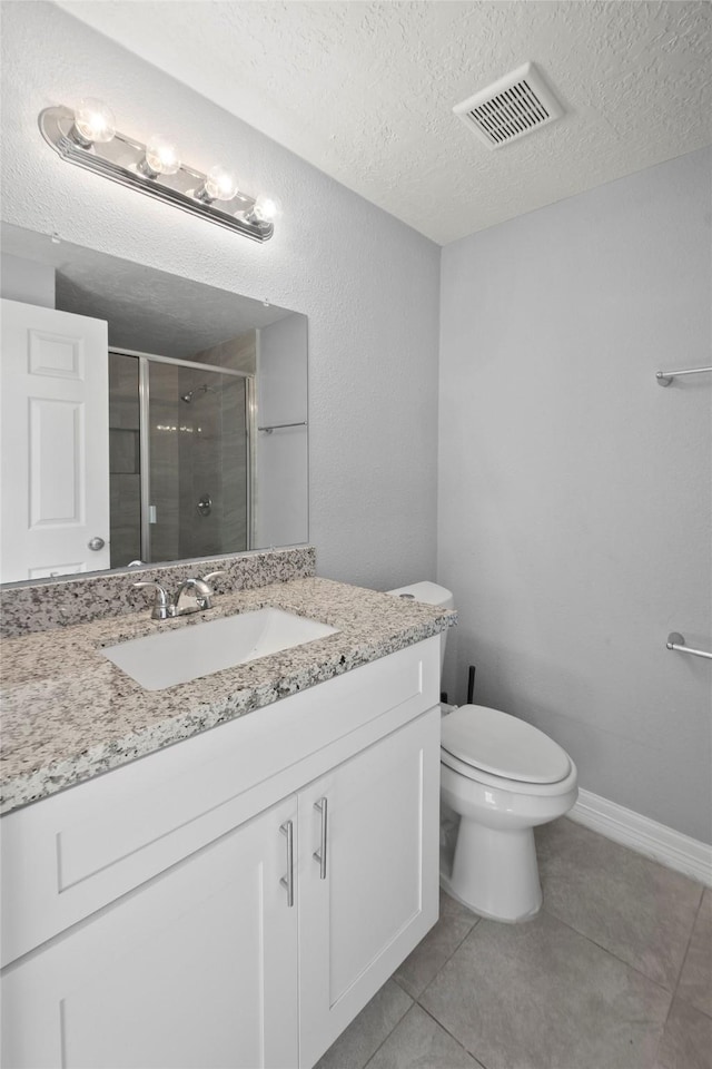 bathroom featuring vanity, tile patterned floors, toilet, a textured ceiling, and an enclosed shower