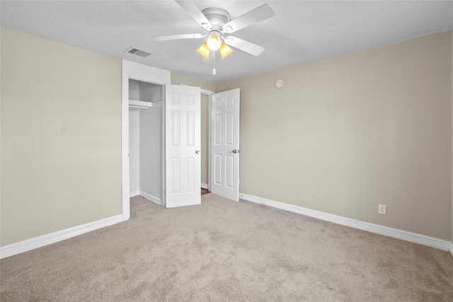 unfurnished bedroom with ceiling fan, light carpet, and a closet