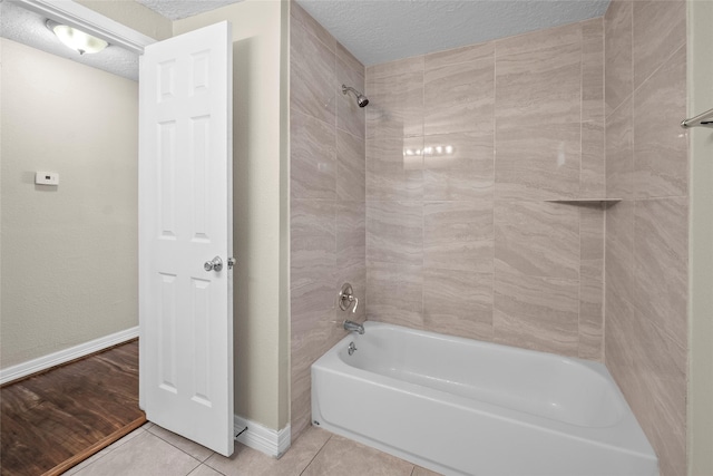 bathroom with tile patterned flooring, tiled shower / bath, and a textured ceiling