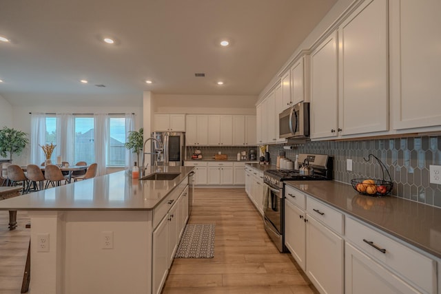 kitchen featuring a spacious island, sink, appliances with stainless steel finishes, tasteful backsplash, and white cabinetry