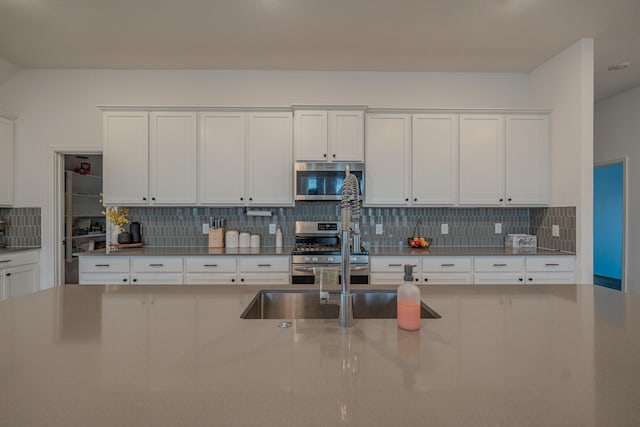 kitchen featuring decorative backsplash, appliances with stainless steel finishes, white cabinetry, and sink