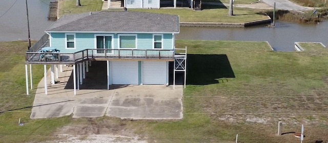 exterior space featuring driveway, a garage, a lawn, a chimney, and a water view