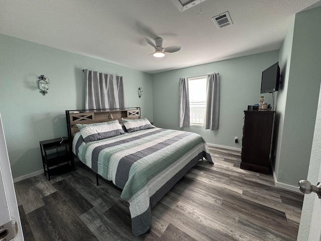 bedroom with dark wood-style floors, visible vents, attic access, a textured ceiling, and baseboards