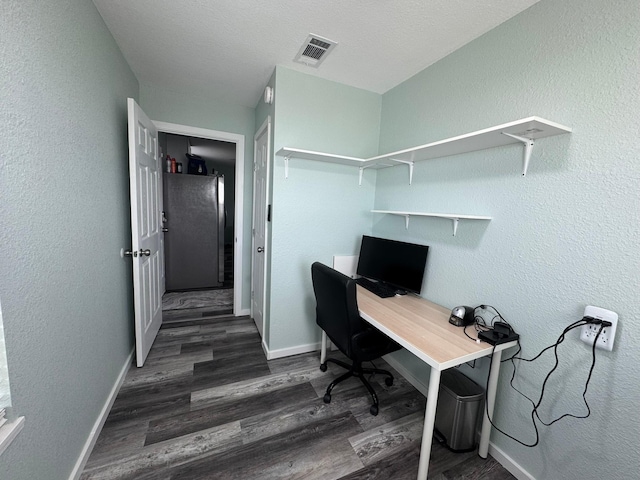 office featuring baseboards, visible vents, wood finished floors, and a textured wall