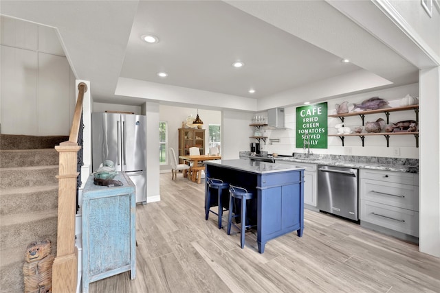 kitchen with a kitchen bar, a center island, light hardwood / wood-style floors, and appliances with stainless steel finishes