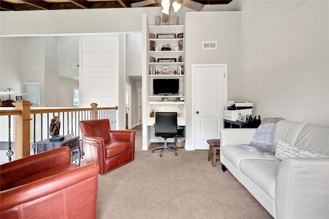 living room featuring carpet flooring, ceiling fan, a towering ceiling, and beamed ceiling