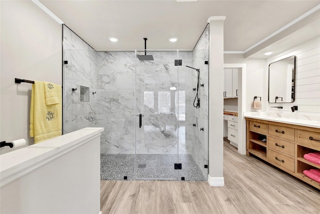 bathroom featuring hardwood / wood-style floors, vanity, walk in shower, and crown molding