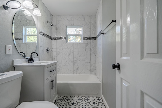 full bathroom featuring tile patterned flooring, vanity, tiled shower / bath combo, and toilet