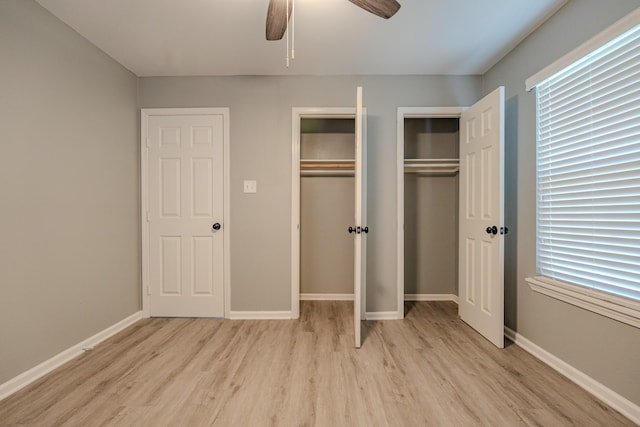 unfurnished bedroom featuring multiple windows, two closets, light hardwood / wood-style floors, and ceiling fan