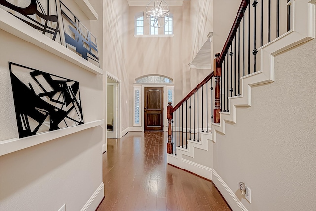 foyer featuring hardwood / wood-style floors, a towering ceiling, and a notable chandelier