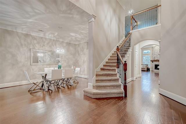 entrance foyer with hardwood / wood-style floors, a fireplace, a high ceiling, and a chandelier