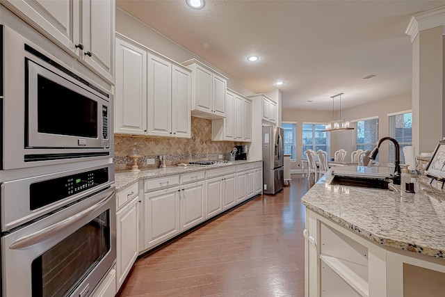 kitchen featuring an inviting chandelier, sink, hanging light fixtures, white cabinetry, and stainless steel appliances