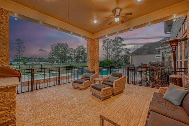 patio terrace at dusk with a fenced in pool, outdoor lounge area, and ceiling fan