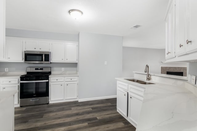 kitchen with light stone countertops, white cabinets, appliances with stainless steel finishes, dark wood-type flooring, and sink