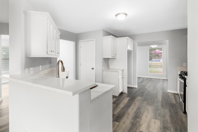 kitchen featuring white cabinets, kitchen peninsula, dark hardwood / wood-style flooring, and gas stove