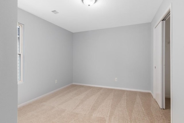 unfurnished bedroom featuring light carpet, a closet, and multiple windows