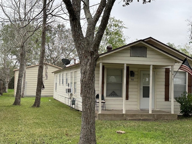 bungalow-style home with a front yard, covered porch, and cooling unit