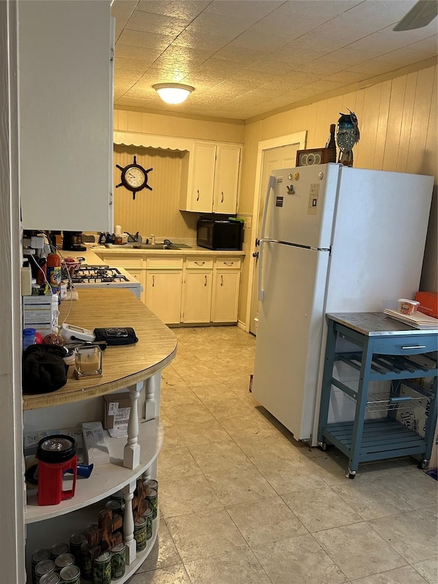 kitchen featuring sink, wooden walls, and white appliances