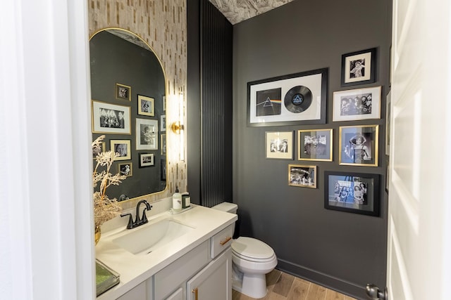 bathroom with toilet, vanity, and hardwood / wood-style floors