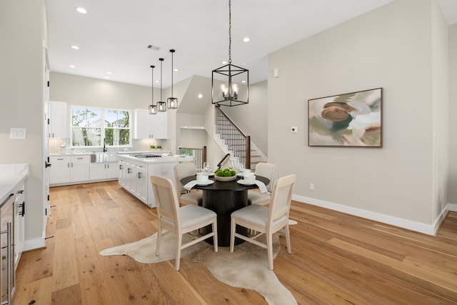 kitchen featuring sink, decorative light fixtures, light hardwood / wood-style flooring, white cabinets, and a center island