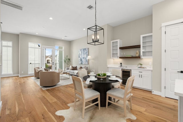 dining room featuring light hardwood / wood-style floors, wine cooler, and a chandelier