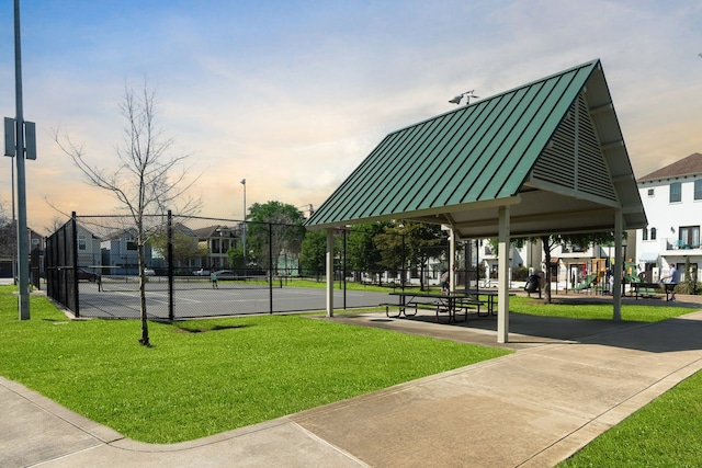 view of home's community featuring a yard and tennis court