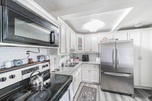 kitchen featuring light stone countertops, white cabinetry, sink, stainless steel appliances, and light hardwood / wood-style flooring