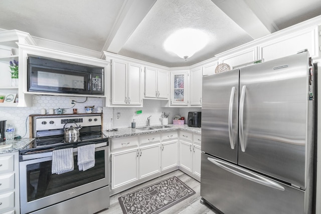 kitchen with white cabinetry, sink, light stone counters, and appliances with stainless steel finishes