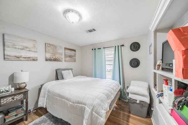 bedroom with wood-type flooring and a textured ceiling