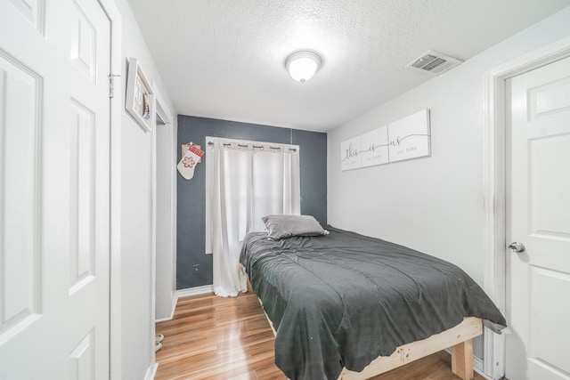 bedroom featuring light hardwood / wood-style flooring and a textured ceiling