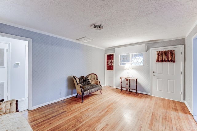 sitting room featuring a textured ceiling, light hardwood / wood-style floors, and ornamental molding