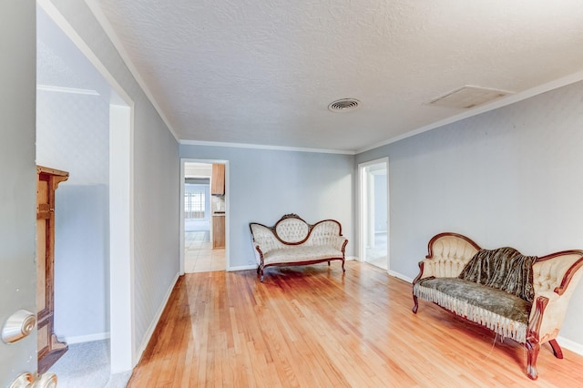 living area featuring wood-type flooring, a textured ceiling, and ornamental molding