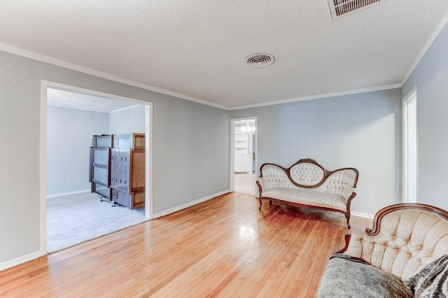 living area featuring crown molding, hardwood / wood-style floors, and a textured ceiling