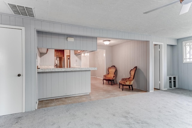 kitchen featuring ceiling fan, stainless steel refrigerator with ice dispenser, kitchen peninsula, a textured ceiling, and light carpet