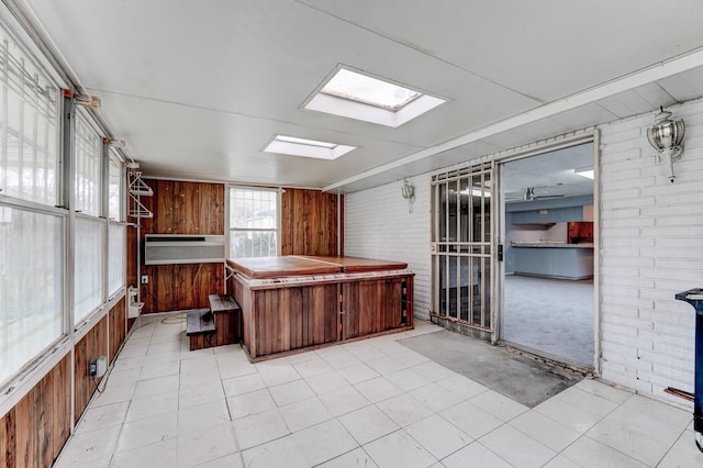 kitchen with a skylight, wooden walls, and brick wall