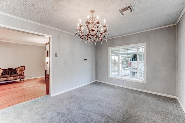 carpeted empty room featuring a textured ceiling, crown molding, and a notable chandelier