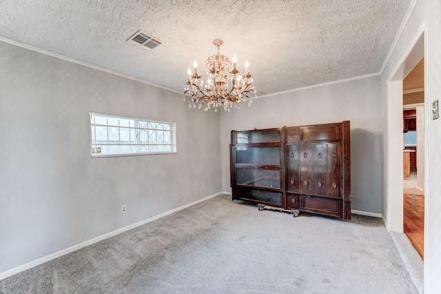 carpeted empty room featuring ornamental molding, a textured ceiling, and an inviting chandelier