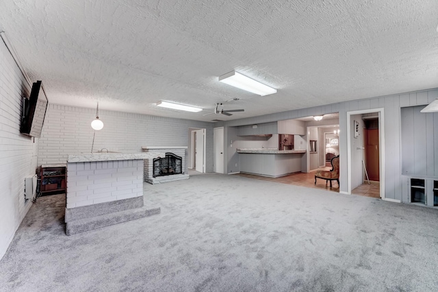 unfurnished living room with ceiling fan, light colored carpet, brick wall, and a textured ceiling