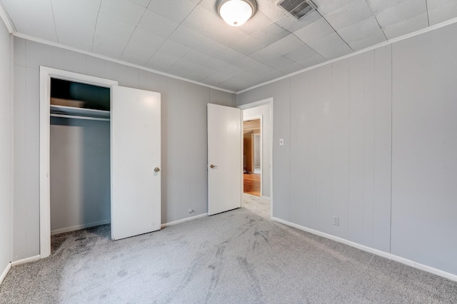 unfurnished bedroom with light colored carpet, a closet, and crown molding