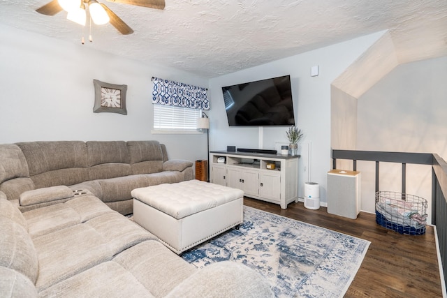 living room featuring ceiling fan, dark wood-type flooring, and a textured ceiling