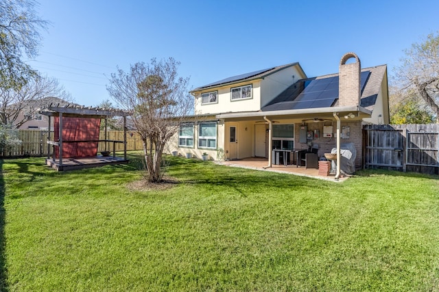 back of property with a patio, a pergola, a yard, and solar panels