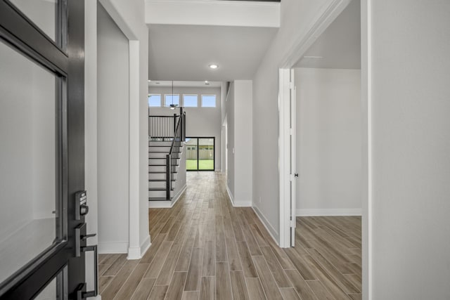 corridor with a high ceiling and light hardwood / wood-style flooring