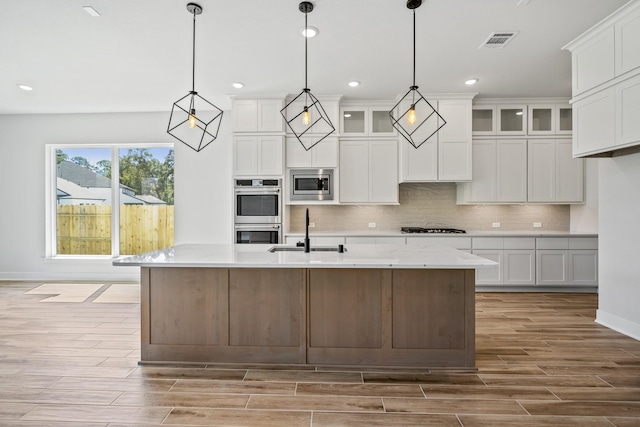 kitchen featuring stainless steel appliances, white cabinetry, hanging light fixtures, and sink