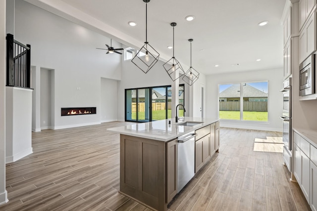 kitchen featuring pendant lighting, a center island with sink, white cabinets, sink, and appliances with stainless steel finishes