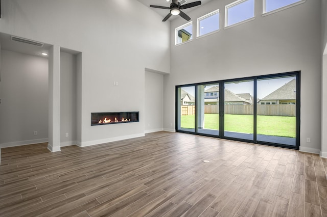 unfurnished living room with ceiling fan and a high ceiling