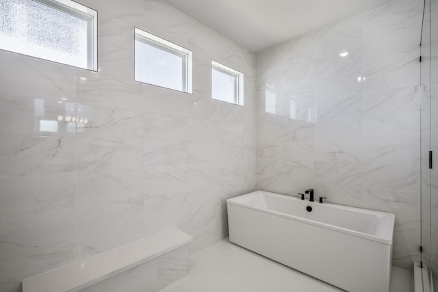 bathroom featuring separate shower and tub, tile walls, and a healthy amount of sunlight