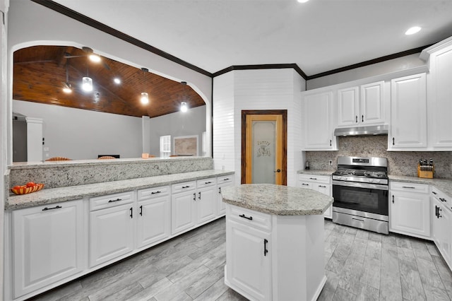 kitchen with light stone countertops, backsplash, vaulted ceiling, white cabinetry, and stainless steel range with gas stovetop