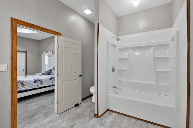 bathroom featuring wood-type flooring,  shower combination, and toilet